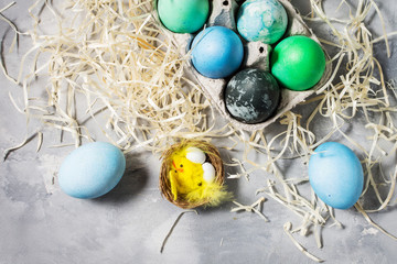 Fototapeta na wymiar painted eggs in tray, chicken eggs, paint and brush on concrete surface, Easter decorations.