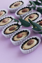 Composition of delicious praline sweets with almonds on purple background