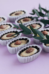 Composition of delicious praline sweets with almonds on purple background