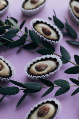 Composition of delicious praline sweets with almonds on purple background