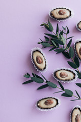 Composition of delicious praline sweets with almonds on purple background