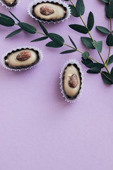 Composition of delicious praline sweets with almonds on purple background