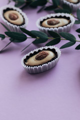 Composition of delicious praline sweets with almonds on purple background