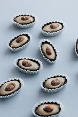 Composition of delicious praline sweets with almonds on blue background