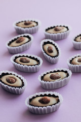 Composition of delicious praline sweets with almonds on purple background