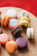Composition of delicious colorful macaroons on wooden board, sweet dessert