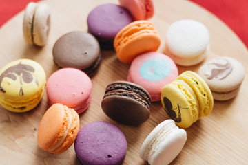 Composition of delicious colorful macaroons on wooden board, sweet dessert