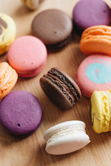 Composition of delicious colorful macaroons on wooden board, sweet dessert