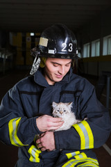 firefighter plays with a kitten, hugs, rejoices