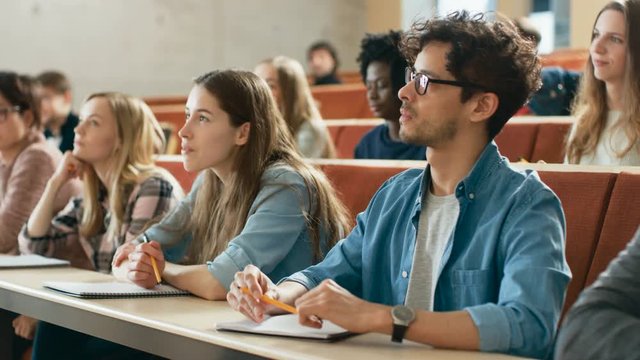 In the University Lecture Hall Multi Ethnic Group of Students Listening Attentively. Auditorium Filled with Smart Young People Eager to Learn. Shot on RED EPIC-W 8K Helium Cinema Camera.