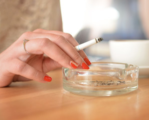 A woman smokes a cigarette and uses an ashtray. Deadly habit. Addiction. Unhealthy.