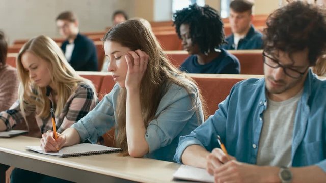Group of Multi Ethnic Students in Classroom Taking Exam/ Test. Bright Young People Study at University. Shot on RED EPIC-W 8K Helium Cinema Camera.