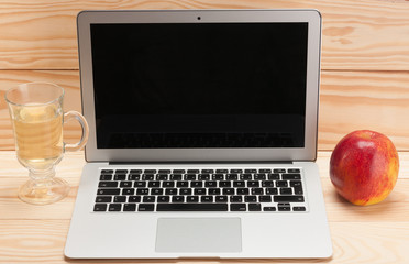 Open laptop with apple on wooden background