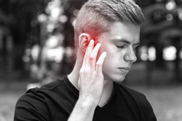 Man suffering from otitis in park