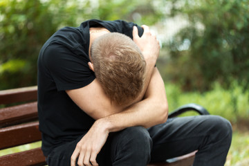 Tired young man are siting on a bench in the park