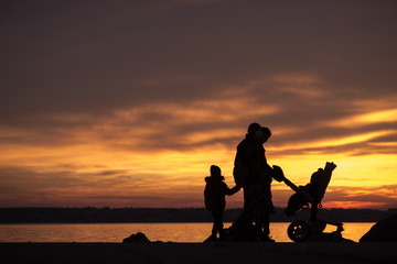 Fototapeta na wymiar Young family silhouetted against an ocean sunset