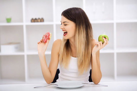 Dieting concept, beautiful young woman choosing between healthy food and junk food