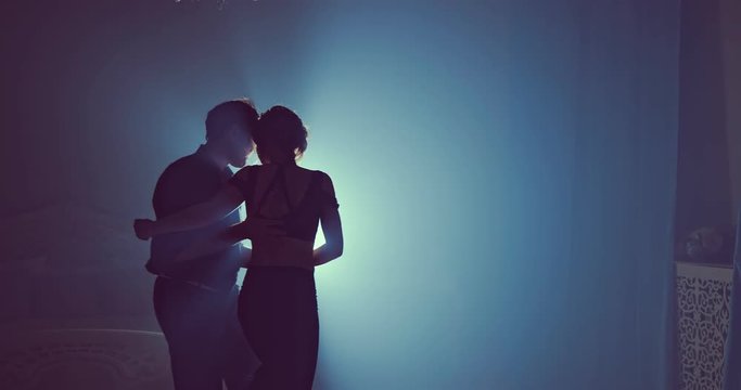 Young couple dance in a dark room with smoke. Slow motion. Silhouette