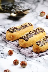 Delicious eclairs with chocolate and hazelnut on the light background. Eclair isolated