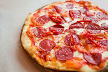 Spicy pizza with cheese and pepperoni. Pepperoni pizza on table.