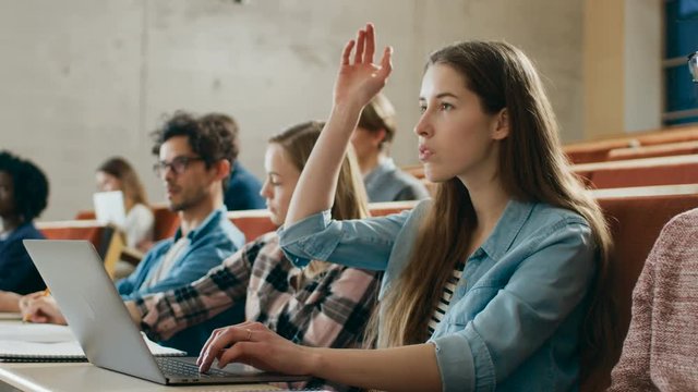 Beautiful Young Student Uses Laptop while Listening to a Lecture at the University, She Raises Hand and Asks Lecturer a Question. Shot on RED EPIC-W 8K Helium Cinema Camera.