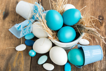 Multi-colored Easter eggs in nest on wooden background, selective focus image. Happy Easter card 