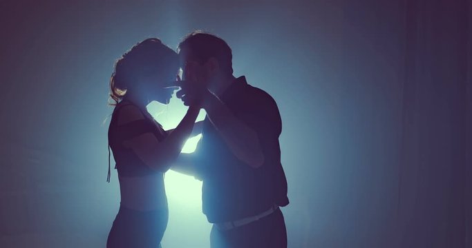 Young couple dancing latin music. Silhouette couple ballroom. Smoke