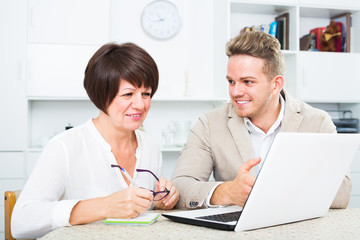 Cheerful mom and son consider software on laptop