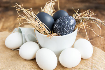 black and white colored Easter eggs in nest on wooden background, selective focus image. Happy...