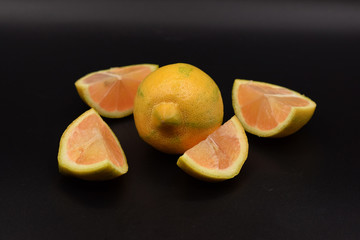Cut pink lemons on a black background. 