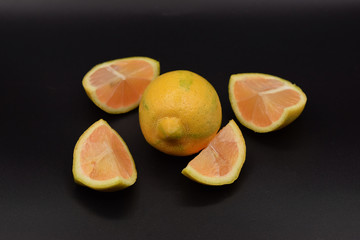 Cut pink lemons on a black background. 