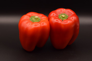 Tasty bright red peppers on a seamless black background. 