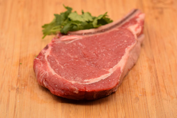 Tenderized steak with salt crystals on wooden cutting board. 