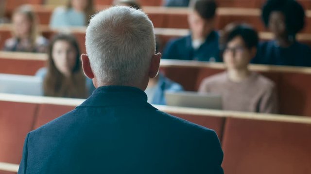 Camera Facing Class: College Professor Gives a Lecture to a Classroom Full of Multi Ethnic Students. Talented Speaker Captures Audience Attention. Shot on RED EPIC-W 8K Helium Cinema Camera.