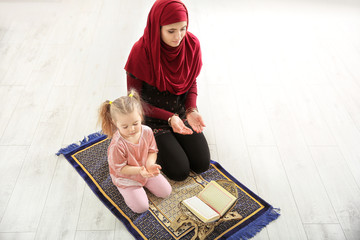 Fototapeta na wymiar Muslim woman praying with her daughter at home