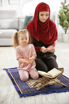 Muslim woman praying with her daughter at home