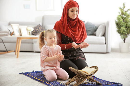 Muslim woman praying with her daughter at home