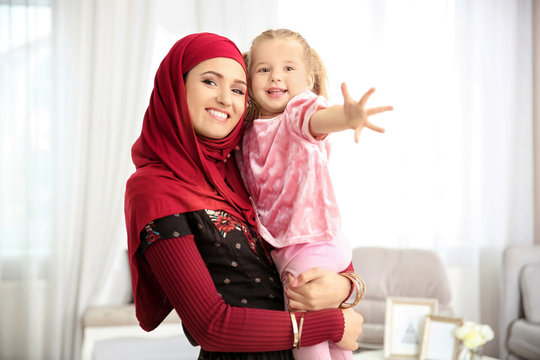 Muslim woman in traditional clothes with her daughter at home