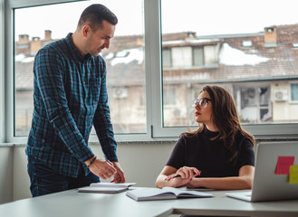 Manager talking angry to his female colleague and writing