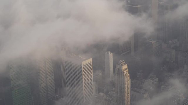 New York City aerial flying though fog and low level clouds at sunrise, with views of Midtown Manhattan skyscrapers on 42nd Street.