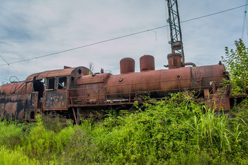 Abandoned train. Abandoned railway. Old rusty steam locomotive overgrown by plants