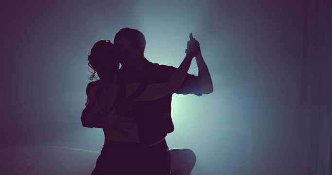 Final point in dances performed by two ballroom dancers. Silhouette in smoky studio