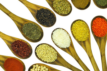 Various colorful legumes, cereals and spices in wooden spoons.