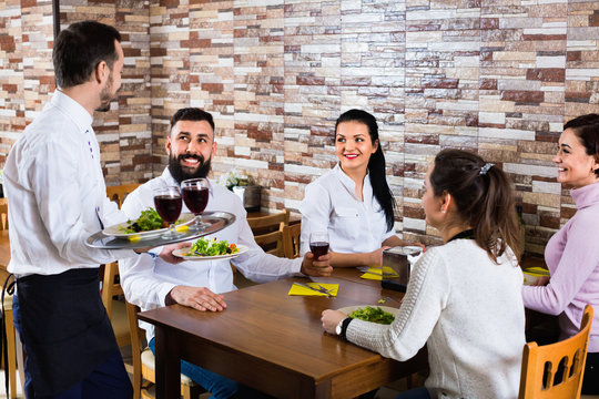 Male waiter carrying order for visitors in country restaurant