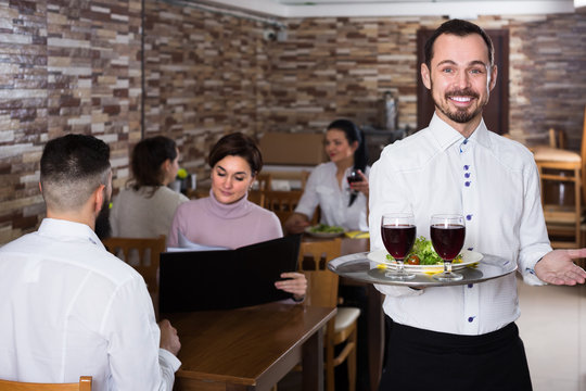 Portrait of adults in middle class restaurant and young waiter