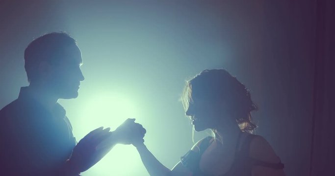 Dancers in love cling to each other at the end of the dance. Silhouette couple ballroom. Smoke