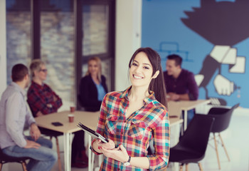 portrait of young business woman at office with team in background