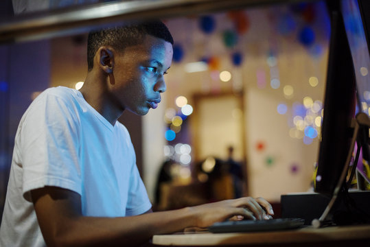 African american boy using a computer at night