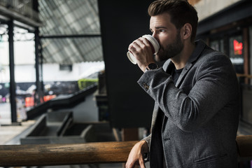 Side view of mna drinking hot coffee