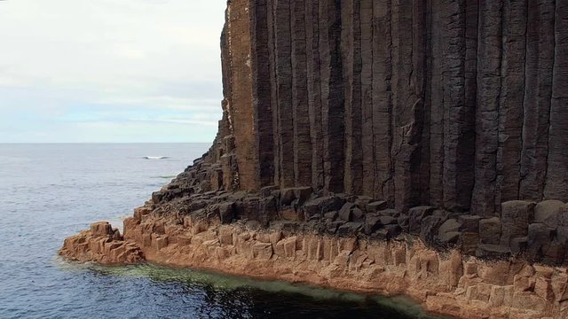 Close-up of vertical basalt columns of Fingal's Cave on Staffa Island, west of Isle of Mull in Scotland. Calm waves touching the rocks. Steady shot in high frame rate.